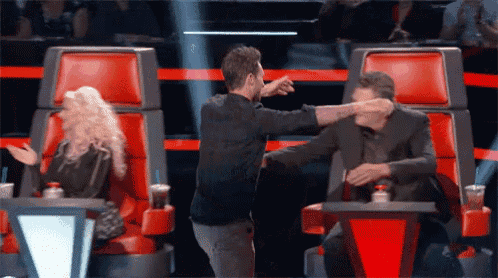 a man giving another man a fist bump while sitting in a red chair