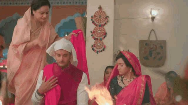 a woman in a pink sari stands next to a man in a red jacket