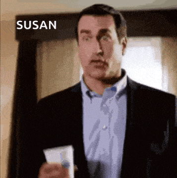 a man in a suit and blue shirt is holding a piece of paper in front of a window .
