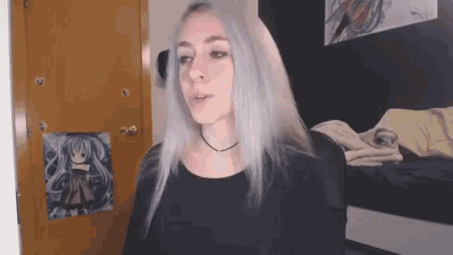a girl with purple hair and a black shirt is standing in a room .