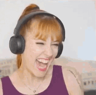 a woman wearing headphones is laughing and smiling with her mouth open .