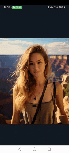 a woman with long blonde hair is standing in front of a canyon