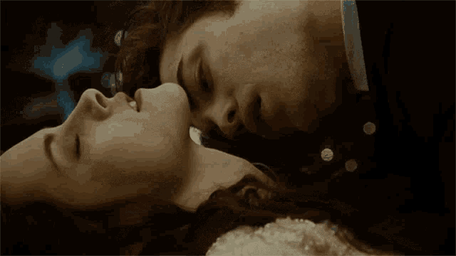 a close up of a man and woman kissing with their eyes closed