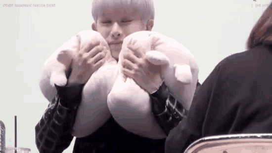 a person is holding a stuffed animal in their arms and making a face .