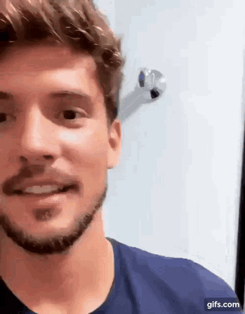 a close up of a man 's face with a beard and a blue shirt .