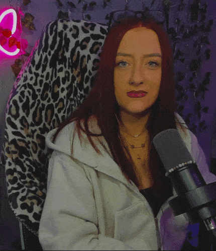 a woman sitting in a chair with a leopard print blanket pointing at the camera