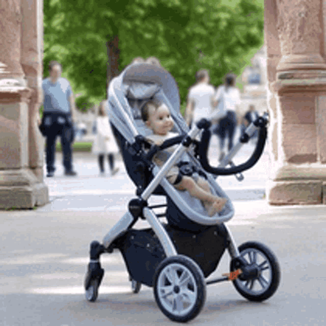 a baby is sitting in a stroller on a sidewalk .