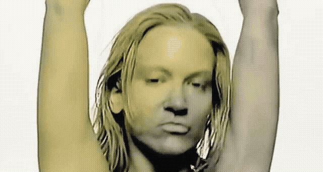 a woman with long blonde hair holds her arms up