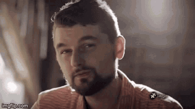 a man with a beard is looking at the camera in a blurry photo .