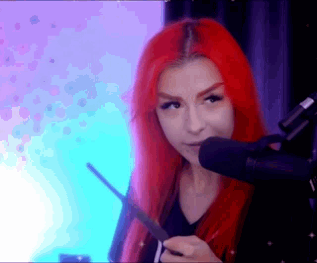 a woman with red hair holding a wand in front of a microphone