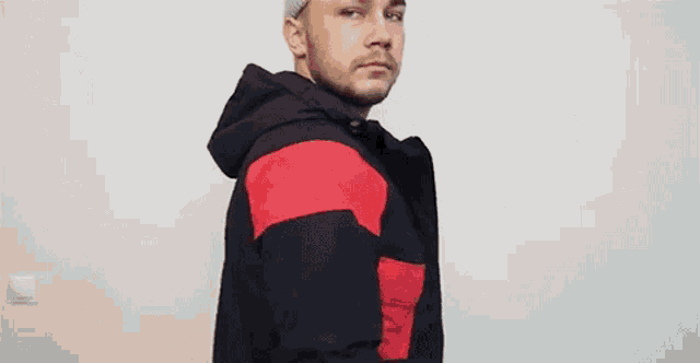 a young man wearing a beanie and a jacket is making a funny face .
