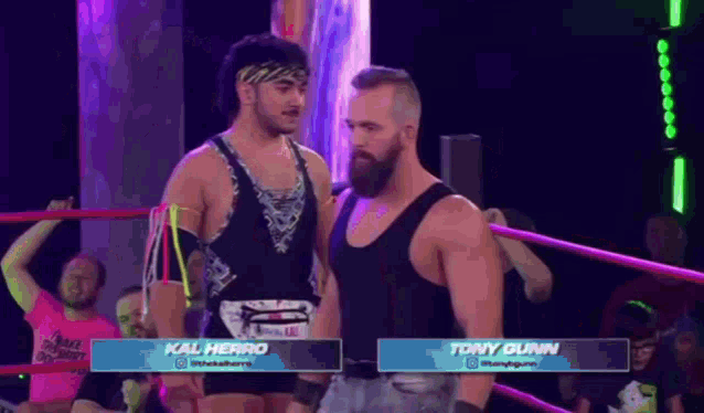 two wrestlers are standing next to each other in a wrestling ring and talking to each other .