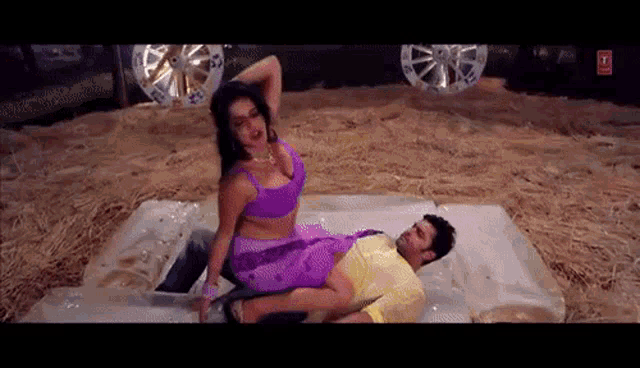 a woman in a purple top is sitting on top of a man
