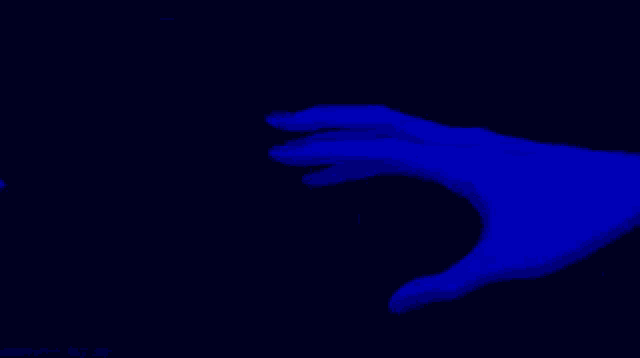 a person is making a heart shape with their hands in a dark room .