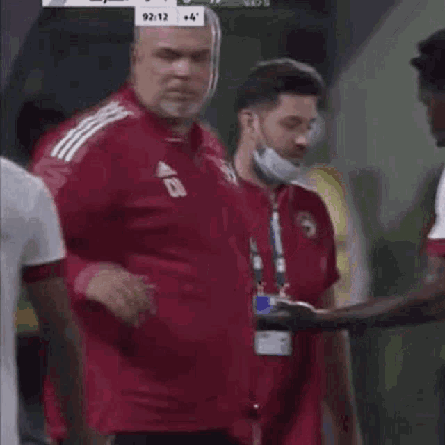 a group of men are standing next to each other on a soccer field wearing face masks .