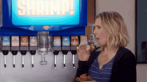 a woman is eating chicken and drinking soda at a soda machine .