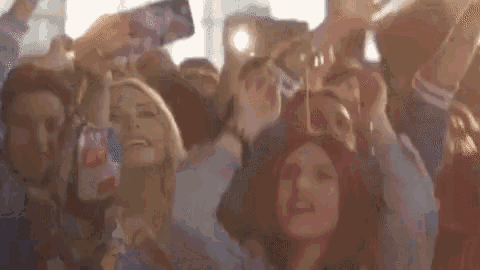a crowd of people are taking pictures of each other with their phones .