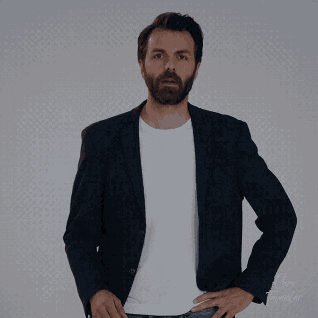 a man with a beard is wearing a blue jacket and a white t-shirt that says cami tavanlar