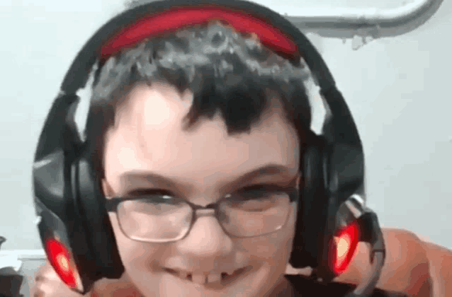 a young boy wearing glasses and headphones is smiling for the camera .