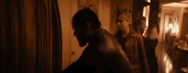 a man with a beard is standing in a dark room with other people .