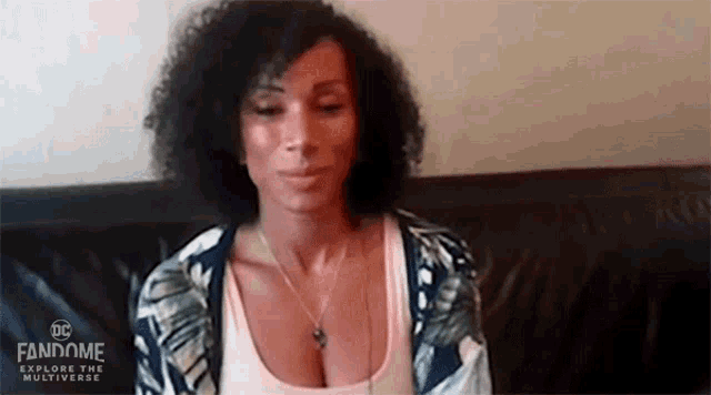 a woman is sitting on a couch with her eyes closed and a necklace on her neck .