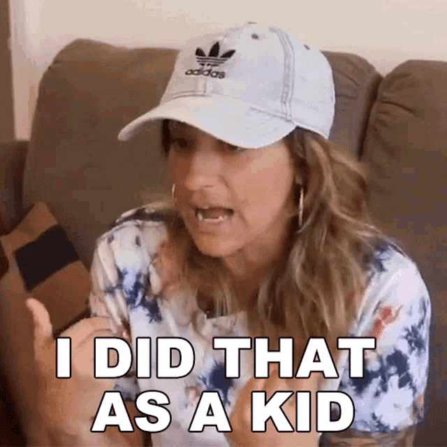 a woman wearing an adidas hat is sitting on a couch and says i did that as a kid