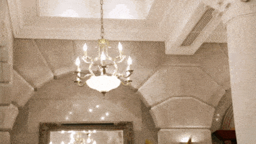 a chandelier is hanging from the ceiling in a room with columns