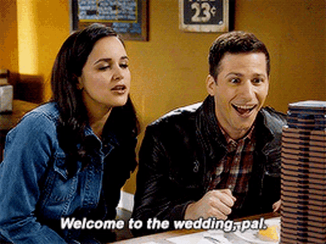 a man and a woman are sitting at a table with the man saying welcome to the wedding pal