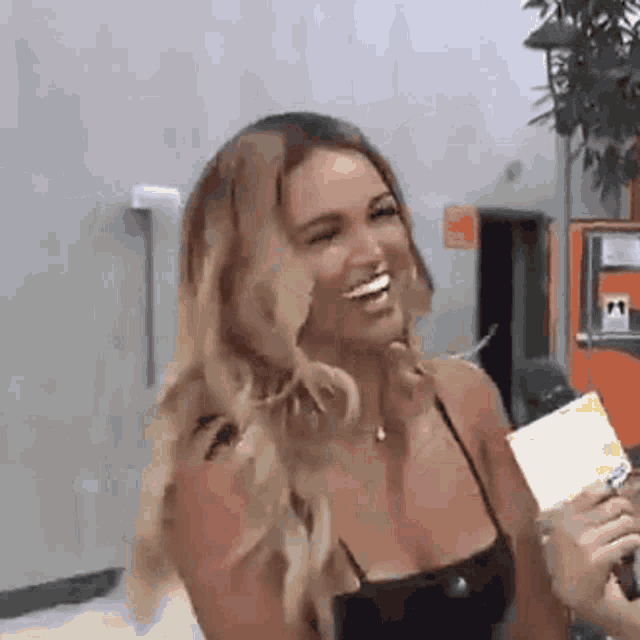 a woman is laughing while holding a microphone in front of her face .