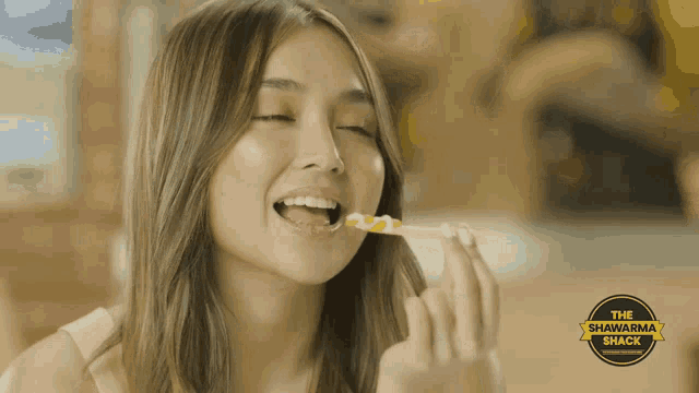 a woman is eating a sandwich from the shawarma shack restaurant