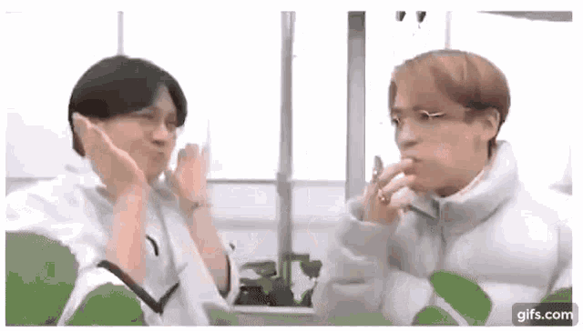 a couple of men are standing next to each other in a room and making funny faces .