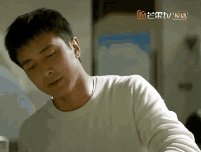 a man in a white shirt is sitting in front of a tv screen that says mtv