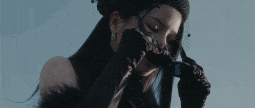 a woman wearing a black veil and gloves is covering her face with her hand .