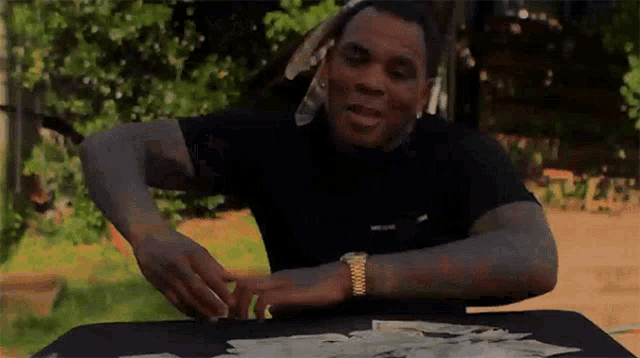 a man is sitting at a table with a bunch of money on it .