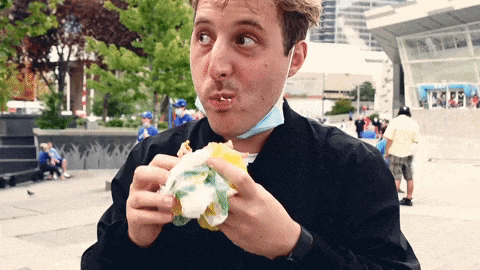 a man wearing a face mask eating a sandwich