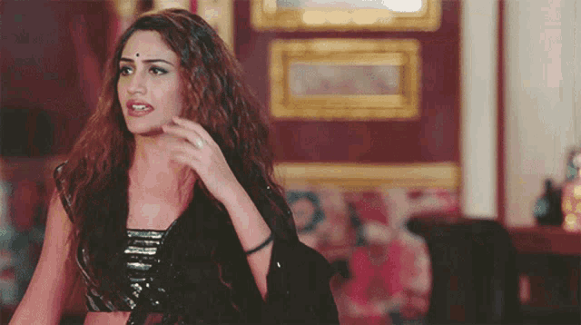 a woman with long hair and a bindi on her forehead looks at the camera