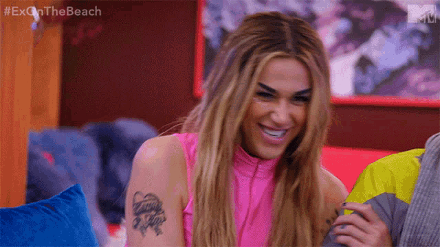 a woman with a tattoo on her arm is sitting on a couch and smiling