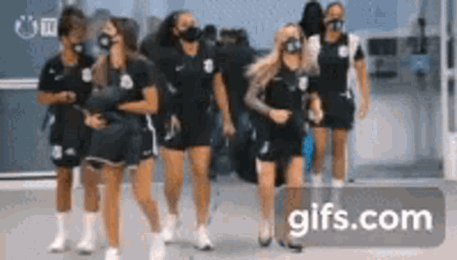 a group of women wearing face masks are walking in a line .
