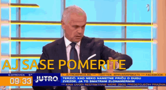 a man in a suit and tie stands in front of a news report that says aj sase pomerite