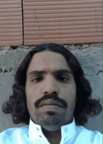a man with long hair and a beard looks at the camera