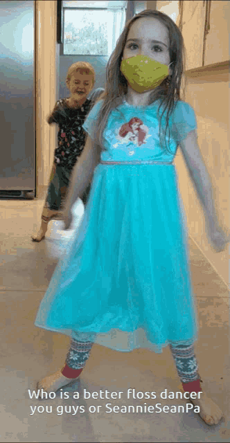 a little girl wearing a green face mask is dancing