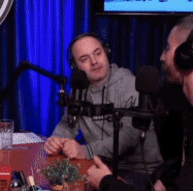 two men are sitting in front of microphones in a studio