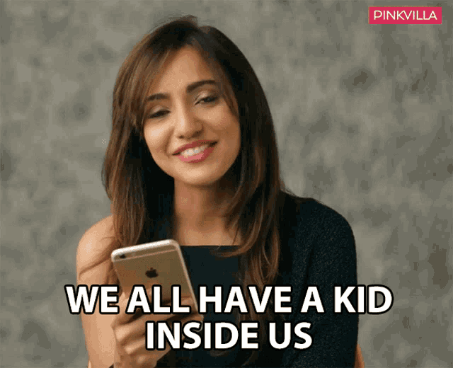 a woman is smiling while looking at her phone with the words we all have a kid inside us below her