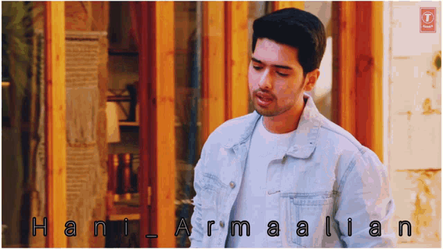 a man in a denim jacket is standing in front of a wooden building with the name hani armalian written on the bottom