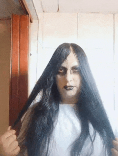 a woman dressed as a ghost is holding her hair in front of her face .