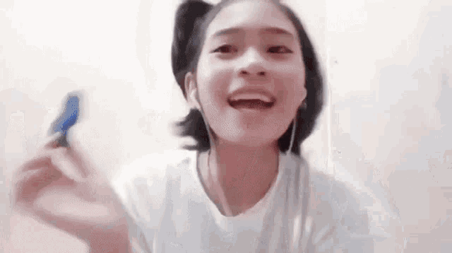a young girl wearing headphones is holding a blue object in her hand .