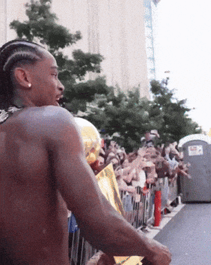 a shirtless man stands in front of a crowd of people