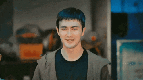 a man with a black shirt and a grey jacket smiles for the camera