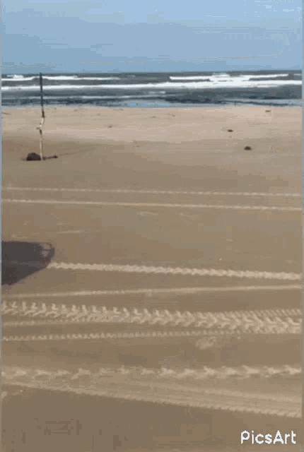 a red atv is driving on a sandy beach .