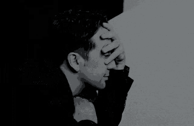 a black and white photo of a man holding his head